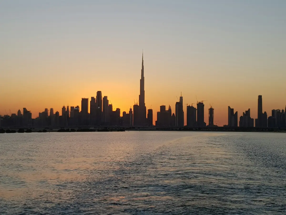 Dubai skyline silhouetted at sunset over the water
